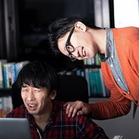 並んでノートパソコンを見る2人の男性の写真