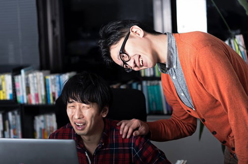 並んでノートパソコンを見る2人の男性