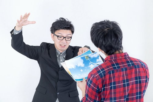 ヤシの木の写真を持つスーツの男性とチェックシャツの男性