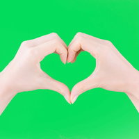 緑背景でハートマークを作る両手のジェスチャーの写真
