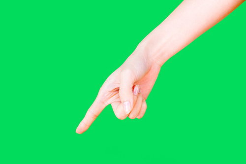 下に指をさす女性の手、グリーンバック背景の写真