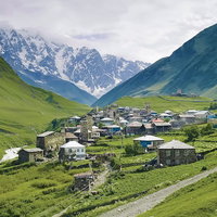 山岳に囲まれた谷間の石造りの街のグルジアの風景の写真