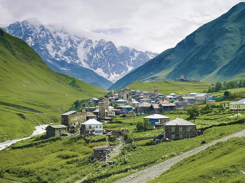 山岳に囲まれた谷間の石造りの街のグルジアの風景
