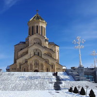 雪をかぶった山を背景にそびえるグルジアの教会の写真