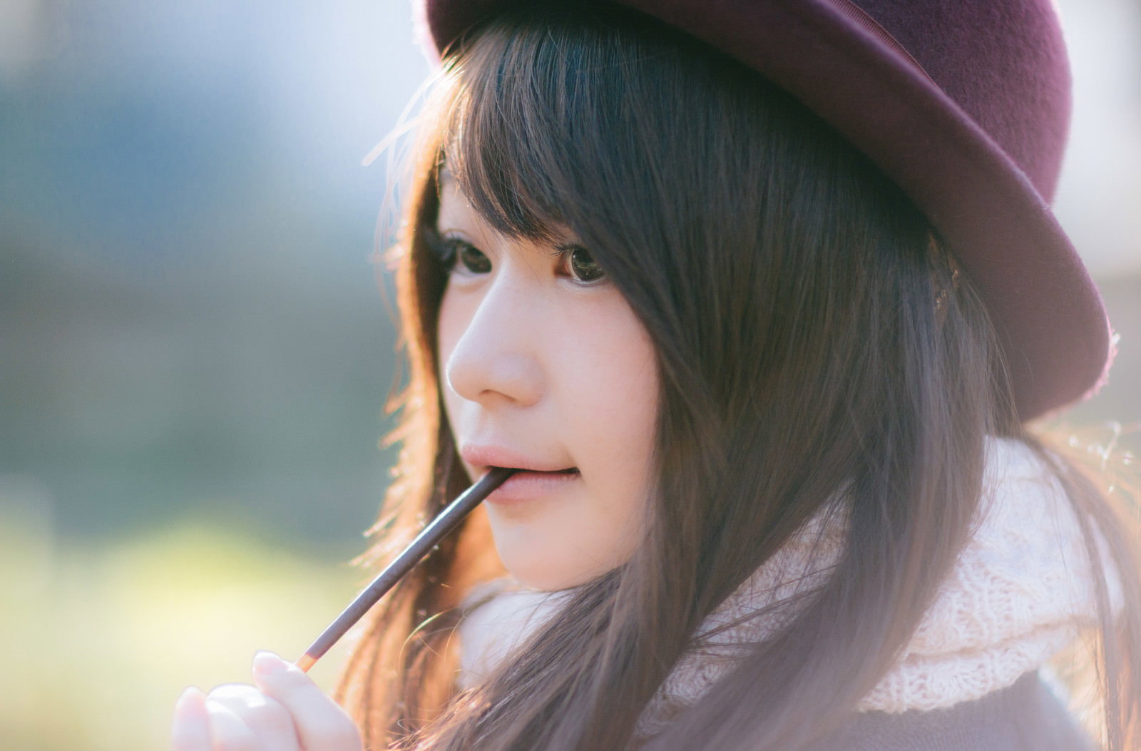 紫のニット帽を被りポッキーをくわえる女性が横向きで微笑んでいる［モデル：茜さや］