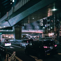 日が暮れた渋谷東口歩道橋から見た車と電車が行き交う都市風景の写真