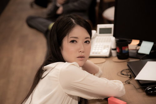 公園の噴水前で無愛想に立つ女性