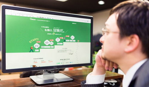 転職サイトが映るモニター画面をぼんやり見るスーツの男性