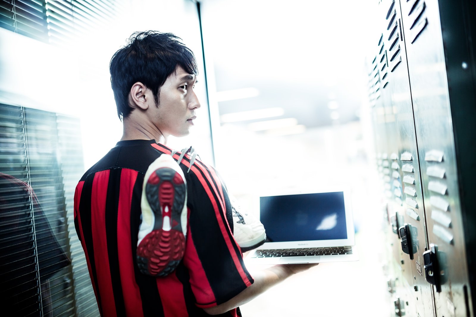 サッカーユニフォームでノートPCを持つ男性［モデル：大川竜弥］
