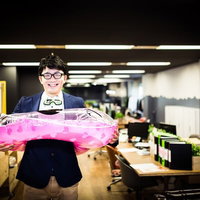 ピンクの透明な浮き輪を持って笑顔のジャケットの眼鏡男性の写真