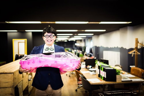 ピンクの透明な浮き輪を持って笑顔のジャケットの眼鏡男性