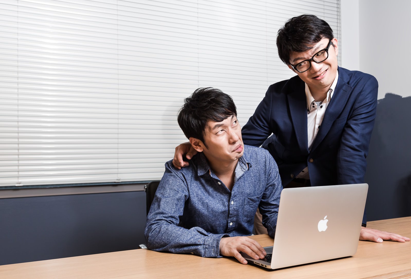 上司に肩を押さえられ困り顔の男性社員［モデル：大川竜弥 OZPA］