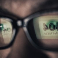 眼鏡のレンズに404 Not Foundの文字が映るアップ写真の写真