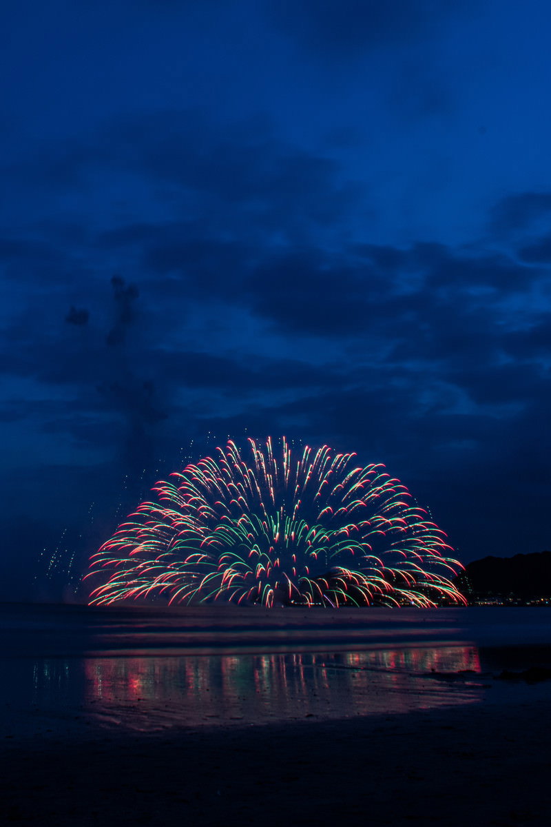 夜空に縦に伸びる赤い打上花火
