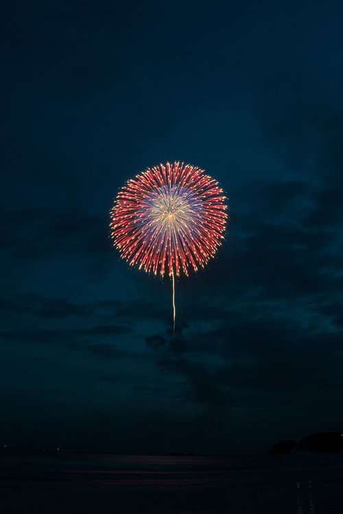 日が落ちてきた夜空に上がる赤と白の打上花火