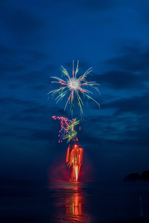 海上から打ち上がる花火大会の夜景