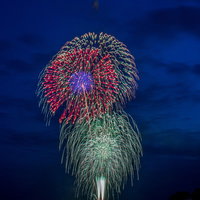 海上で打ち上げられるスターマイン花火の夜景の写真