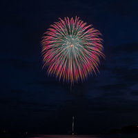 夜空に大きく花咲く赤と白の打上花火の写真