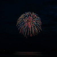 夜空に広がるポンポンのような打上花火が光を放つの写真