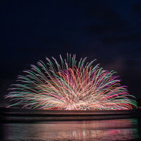 鎌倉花火大会で連発する水中花火と海面への光の反射の写真