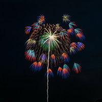 大きい花火と色鮮やかな小さい花火が広がる夜空の写真
