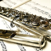 楽譜の上に置かれた銀色のフルートの接写の写真