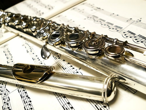 楽譜の上に置かれた銀色のフルートの接写