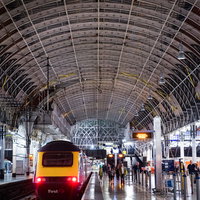 駅のホームから出発する赤い電車車両（海外）の写真