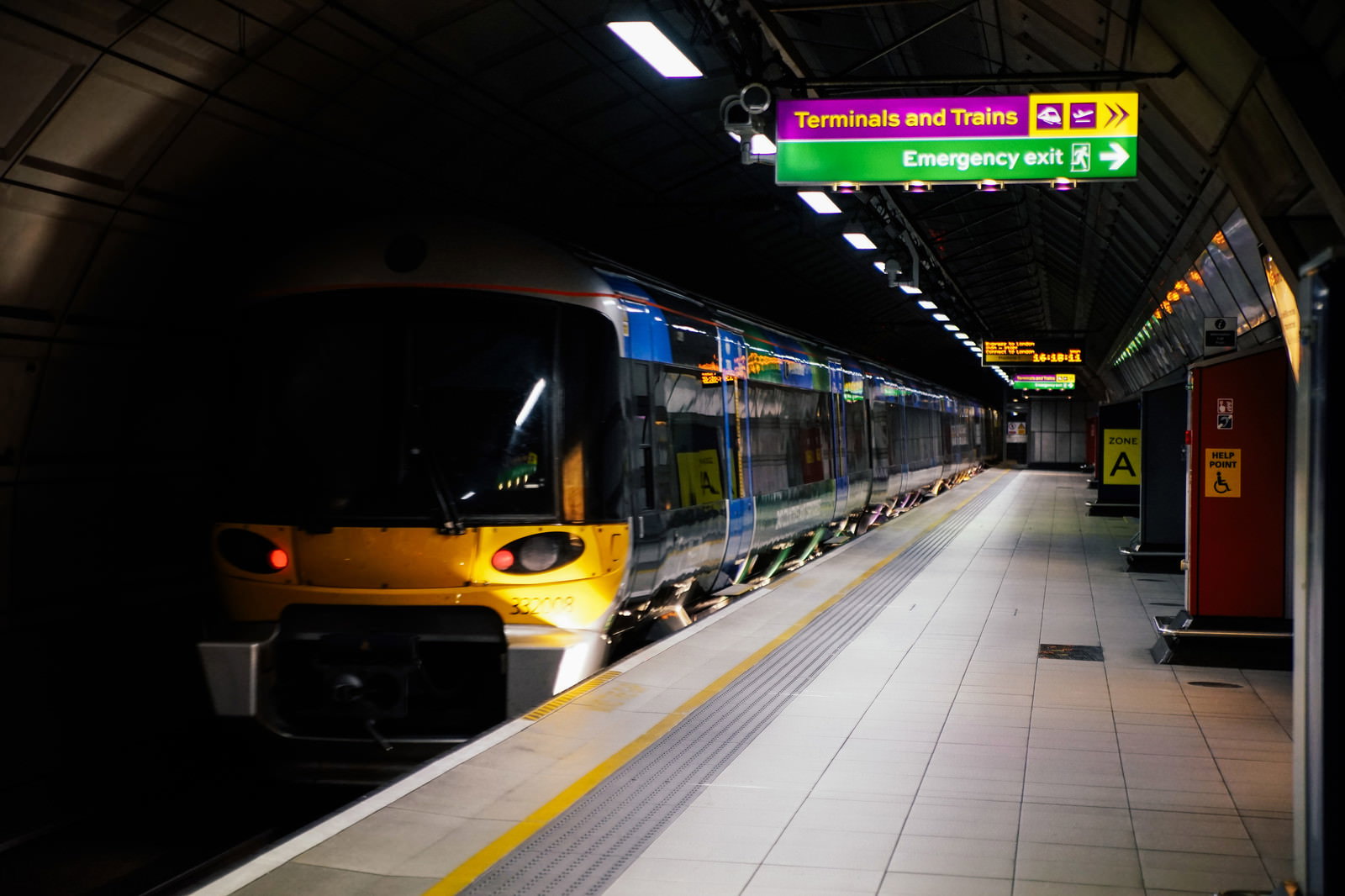 ロンドンの地下鉄駅のホームに停車している黄色いライトの車両