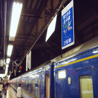 寝台特急北斗星の看板と駅のホーム、停車中の青い車両の写真
