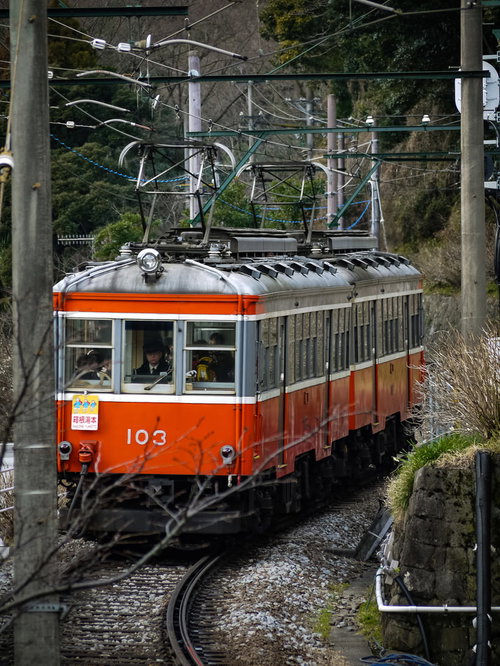 箱根登山鉄道のオレンジ色の電車が走行する線路風景