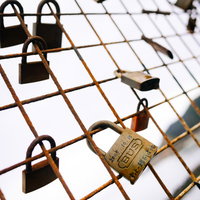 金網に取り付かるメッセージ入りの南京錠と古い鍵の写真