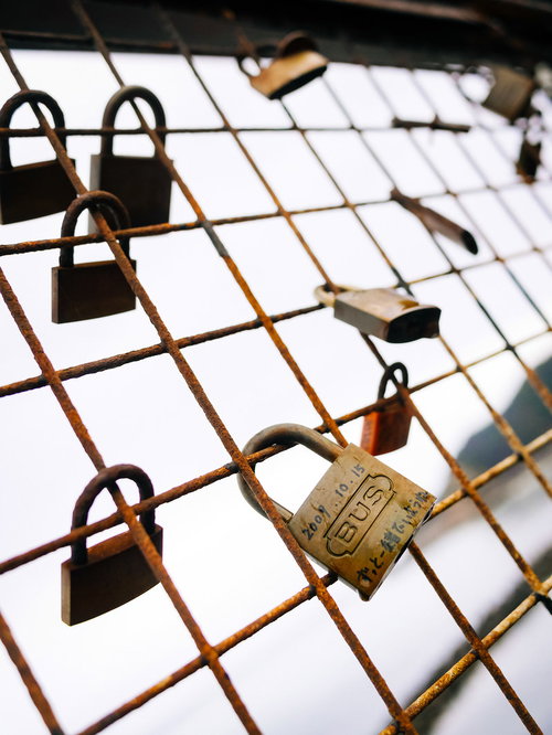 金網に取り付かるメッセージ入りの南京錠と古い鍵