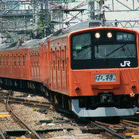 中央線201系の赤橙色電車が線路上に停車している風景の写真