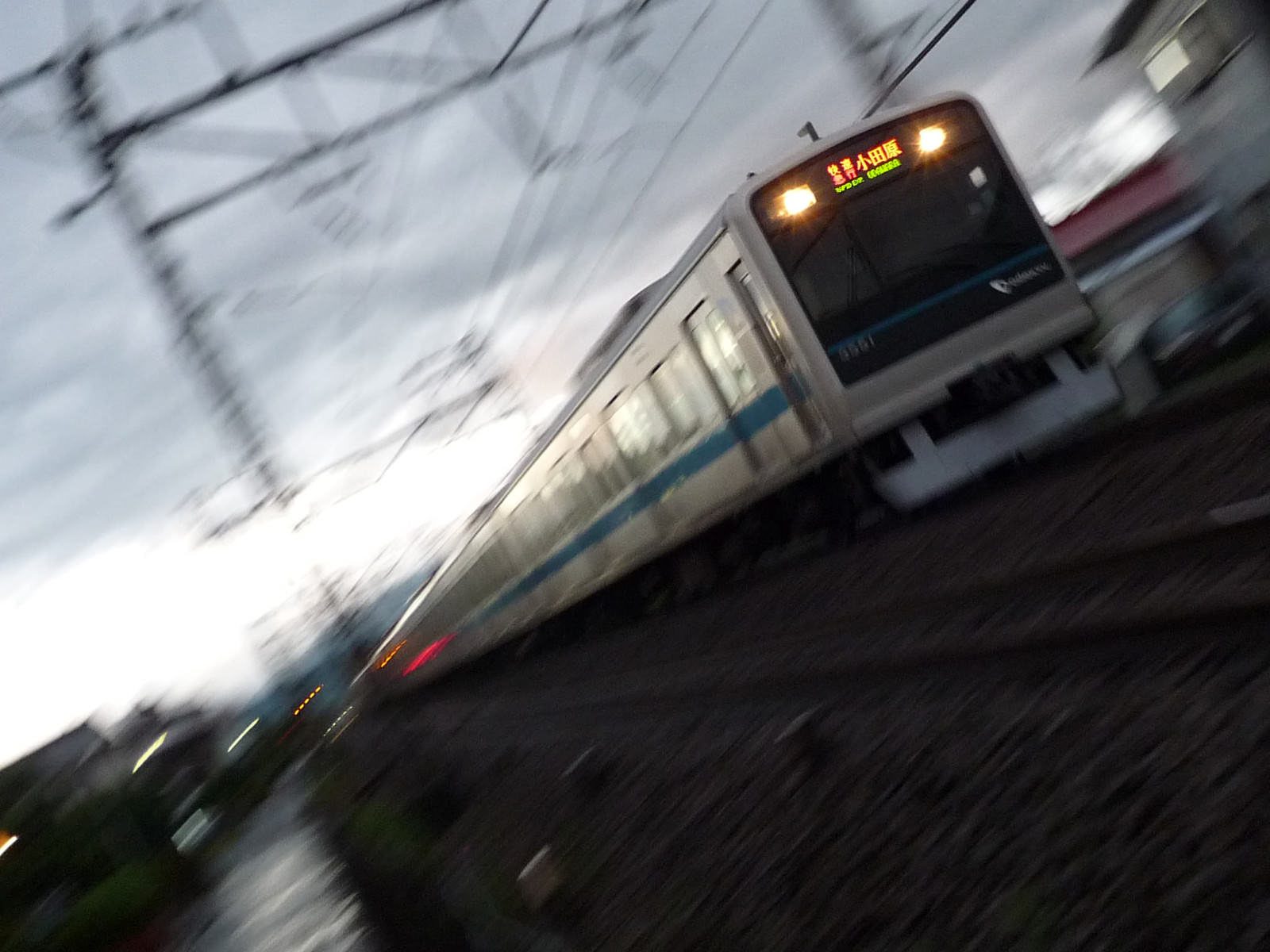 走行中の小田急快速電車と点灯した前照灯