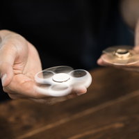 両手にハンドスピナーを握って回すシーン、木製テーブルでの同時回転の写真