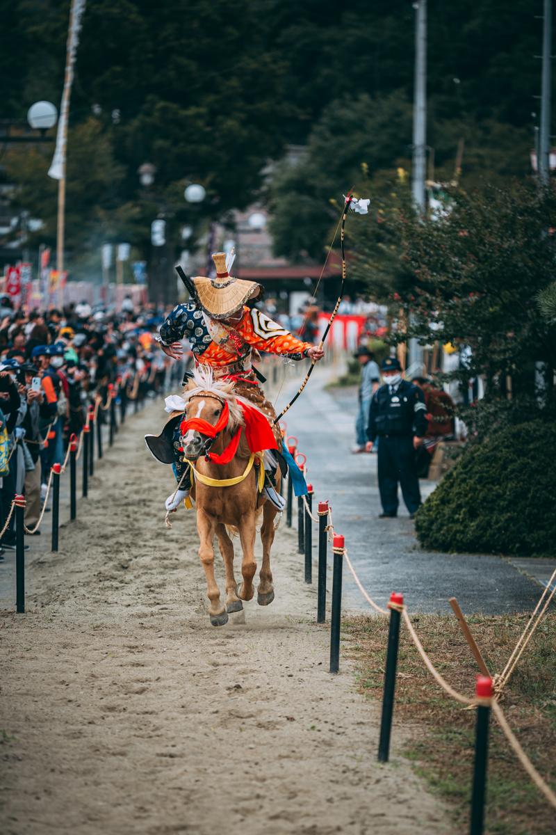 古殿八幡神社で流鏑馬を行う赤い鎧の騎手が馬で駆ける様子