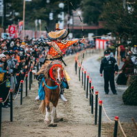 古殿八幡神社の流鏑馬で力強く駆ける馬と騎手の弓の構えの写真