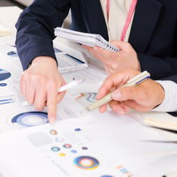 紙に印刷した資料とデータを使ってディスカッションする打合せの写真