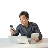 しつこい通知にイライラが隠せない男性がスマートフォンを見て驚くの写真