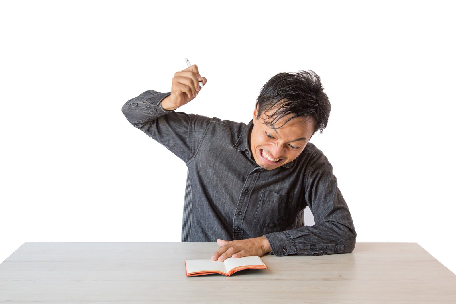 手帳を握りしめて怒りを表現している男性［モデル：藤沢篤］