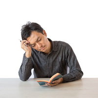 デスクのメモを見つめて考え込む男性の思考風景の写真
