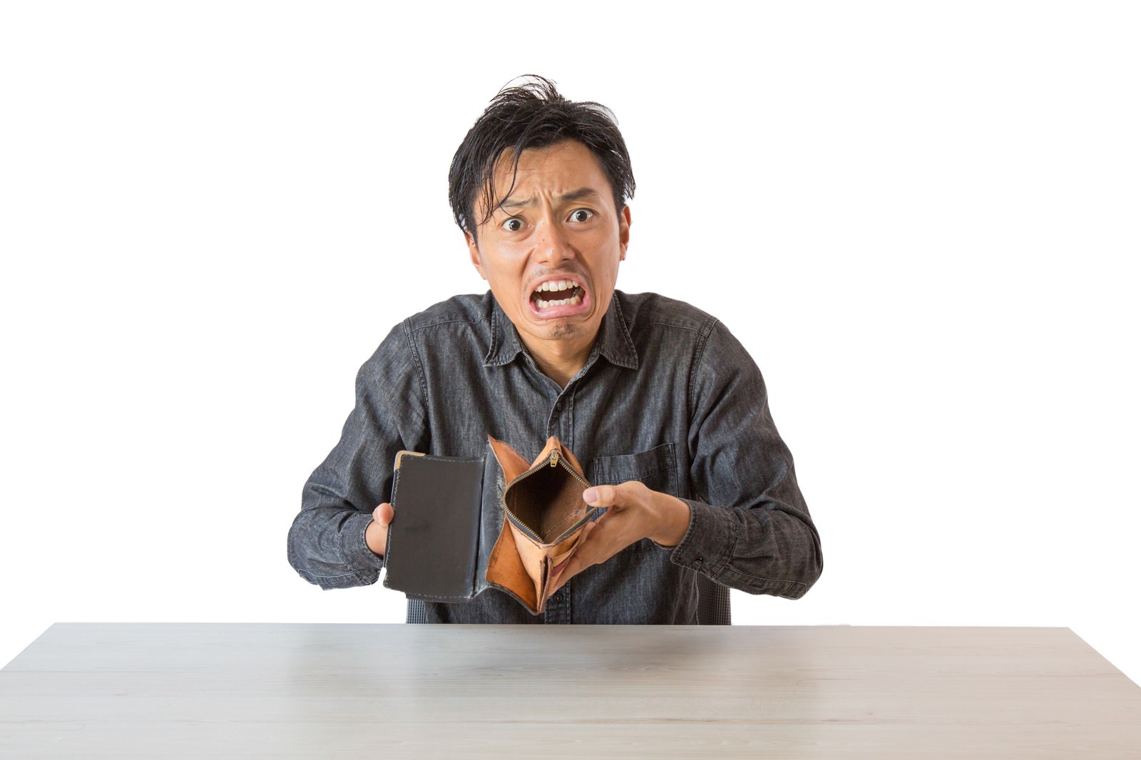 空っぽの財布を持って驚いた表情を見せる男性［モデル：藤沢篤］