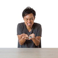 白いテーブルで小銭をかき集める金欠の男性の写真