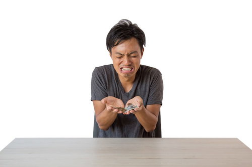 白いテーブルで小銭をかき集める金欠の男性