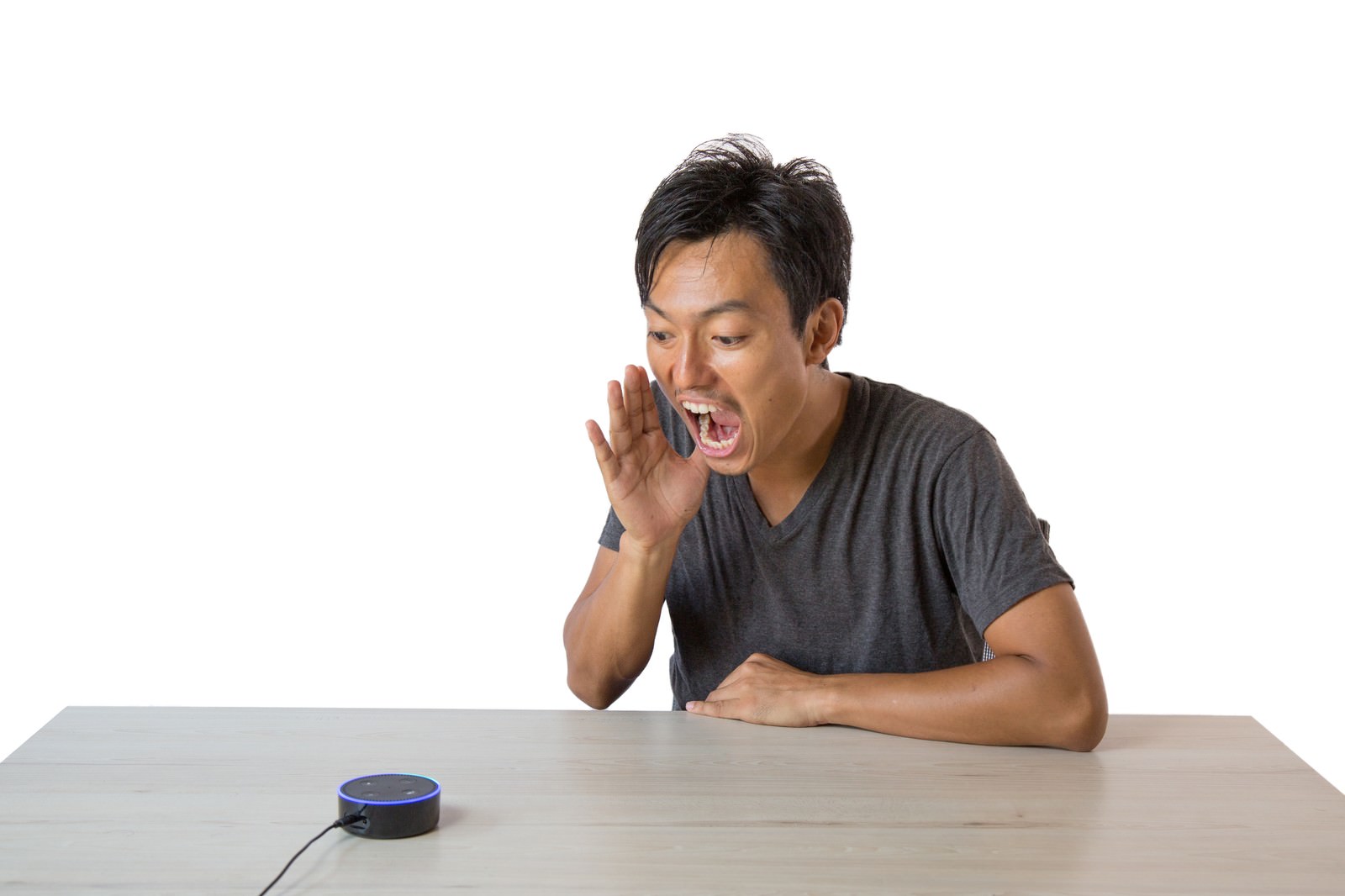 白い背景の前でスマートスピーカーに手を口元に当てて大声で話しかける男性［モデル：藤沢篤］
