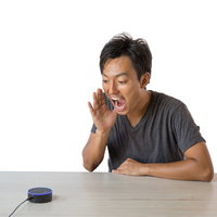 スマートスピーカーに大声で話しかける男性の写真
