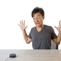 スマートスピーカーのまさかの反応に驚く男性の写真