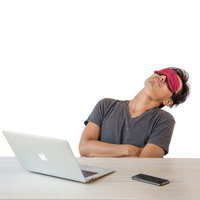 デスクでアイマスクをして仮眠を取る男性の休憩風景の写真