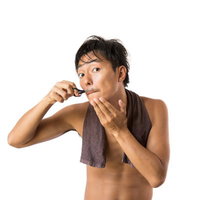 湯上がりに髭トリマーで髭の長さを揃える男性の写真